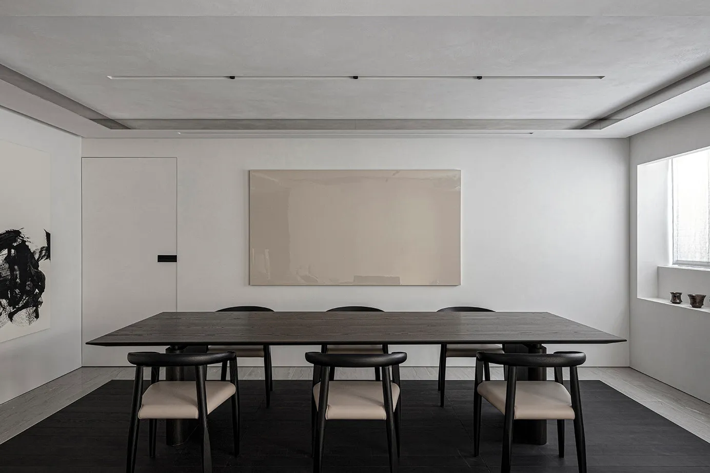 Modern dining room featuring wooden table and black chairs with leather cushions.