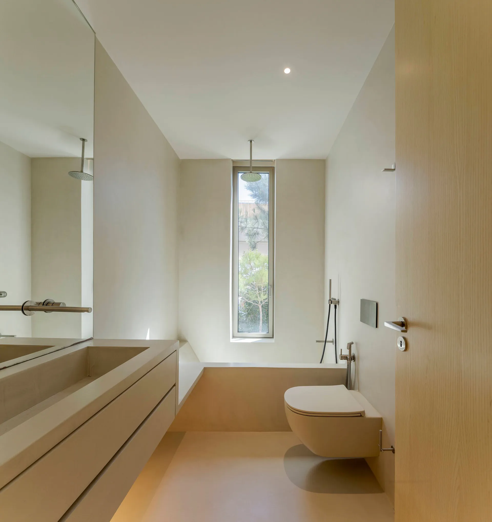 A modern minimalist bathroom with a concrete floor, walls, and sink, featuring a large vertical window.