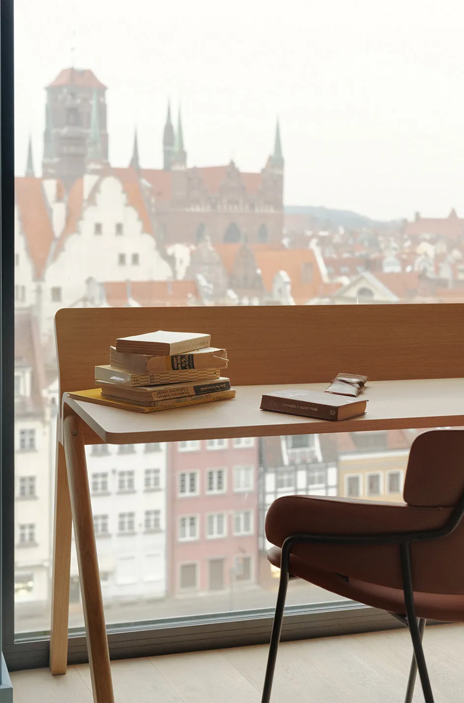 A modern study space featuring a wooden desk, a chair, and books against the backdrop of a cityscape.