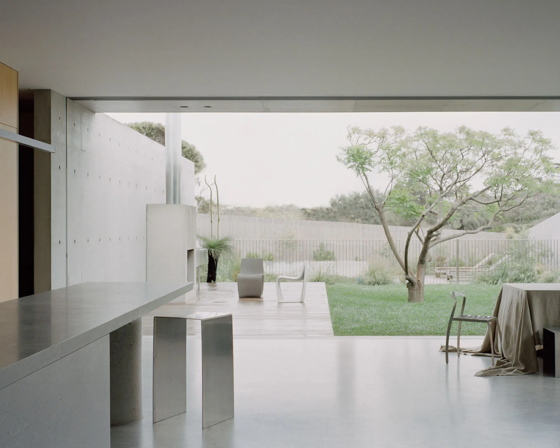 Clean, minimalist residential space featuring modern furniture and a seamless integration of indoor and outdoor elements.