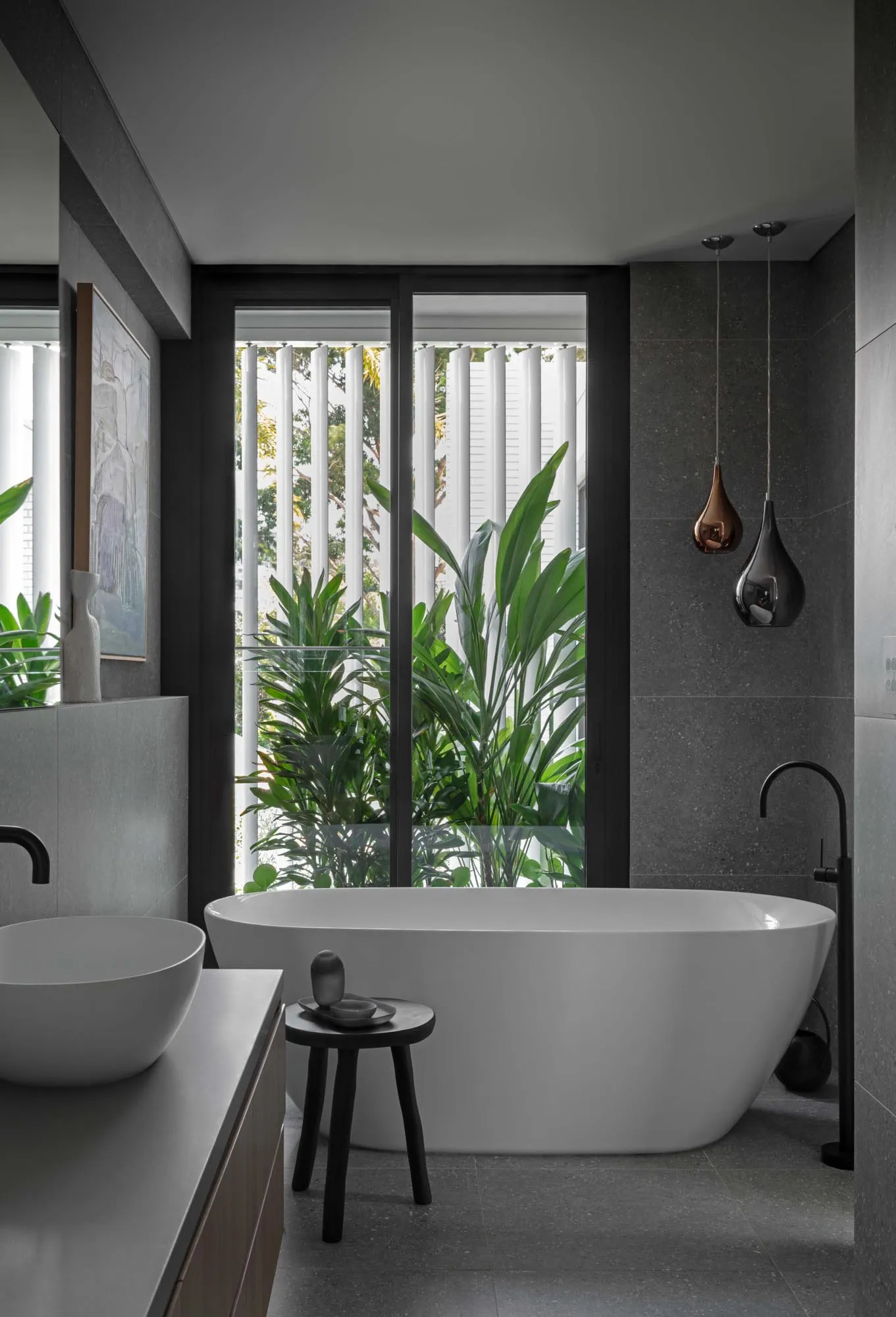 Modern bathroom featuring a large, free-standing white bathtub with smart materials and a dark grey marble floor.