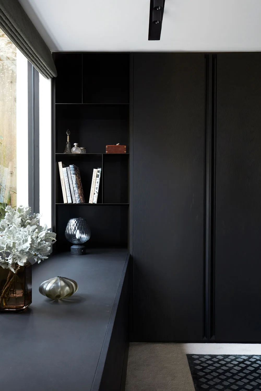 A modern black interior with metallic accents and a glass vase on a shelf.