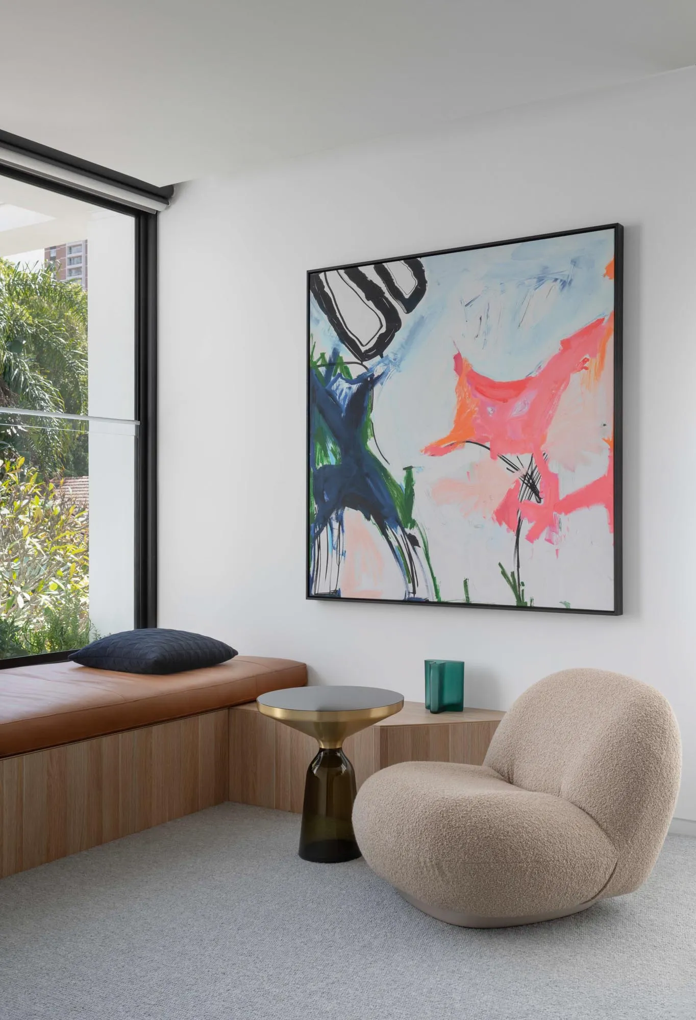 A modern contemporary living room featuring a taupe textured sofa, a wooden side table, a colorful abstract painting, and a l