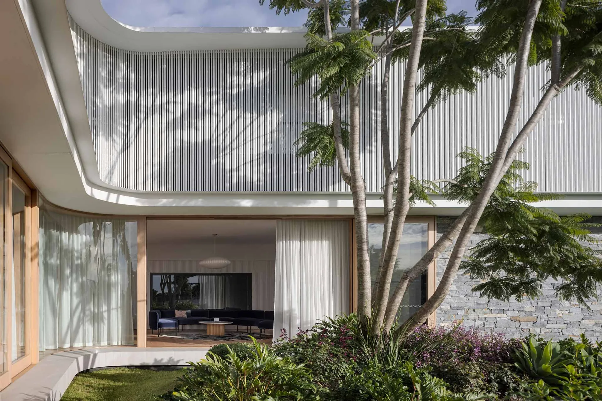 A modern house exterior featuring a metal-cladding facade and large, transparent windows.
