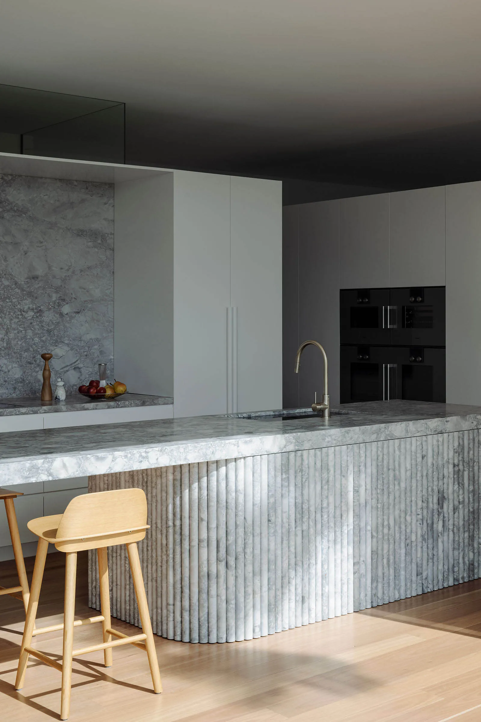 Modern kitchen interior with marble island and stools.