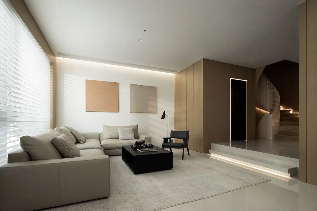 Modern living room with neutral tones, L-shaped sofa, coffee table, and minimalist decor.