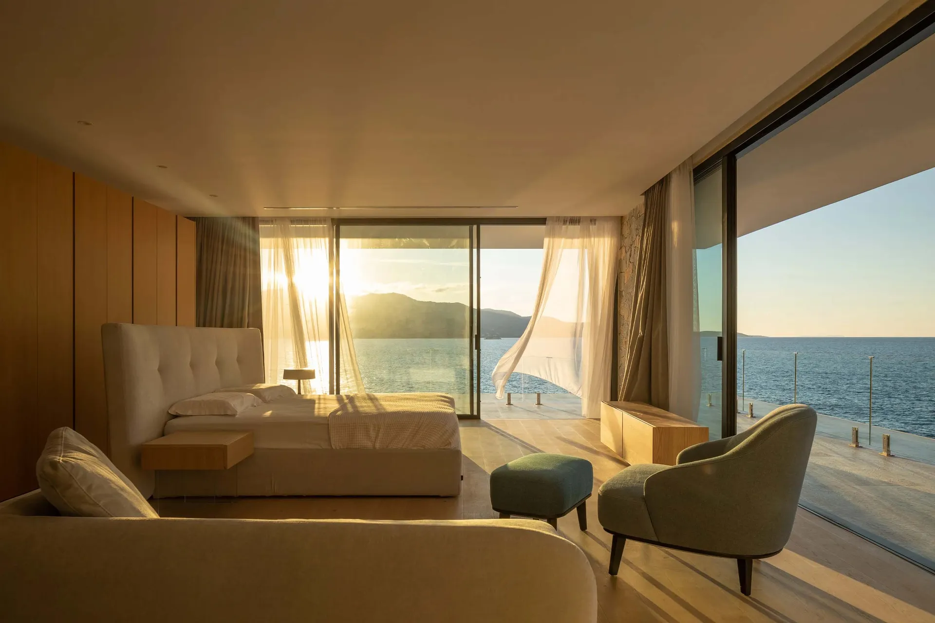 Modern residential interior featuring natural light and neutral tones, with a view of the ocean.