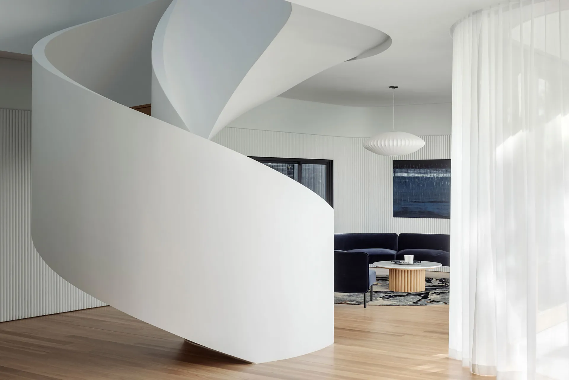 A modern, white, curved staircase made of concrete and wood materials.