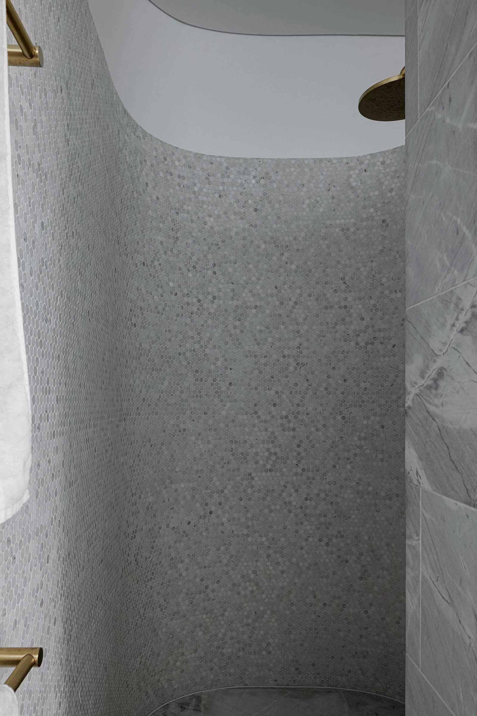 A modern marble shower with tiled walls and overhead rainfall shower head.