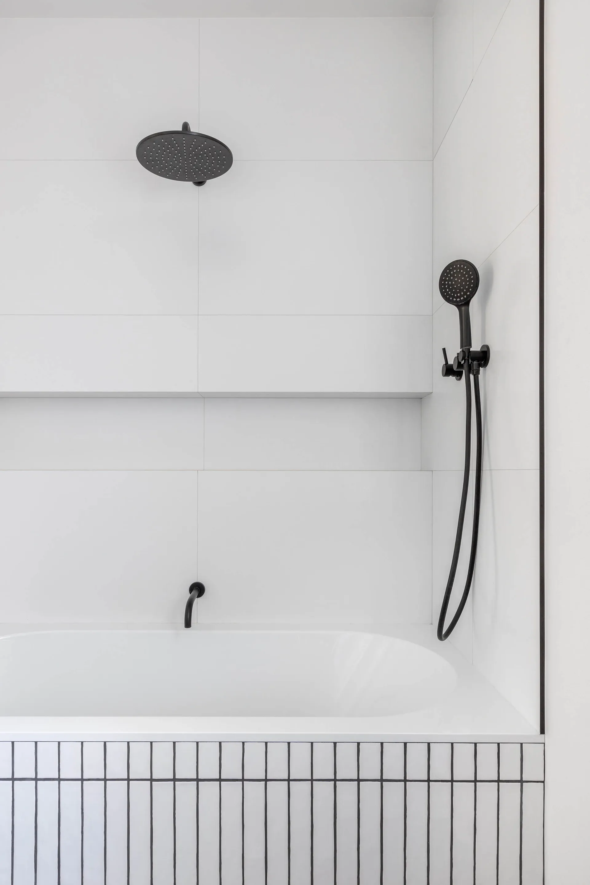 Modern minimalist bathroom with white tile walls and black fixtures.