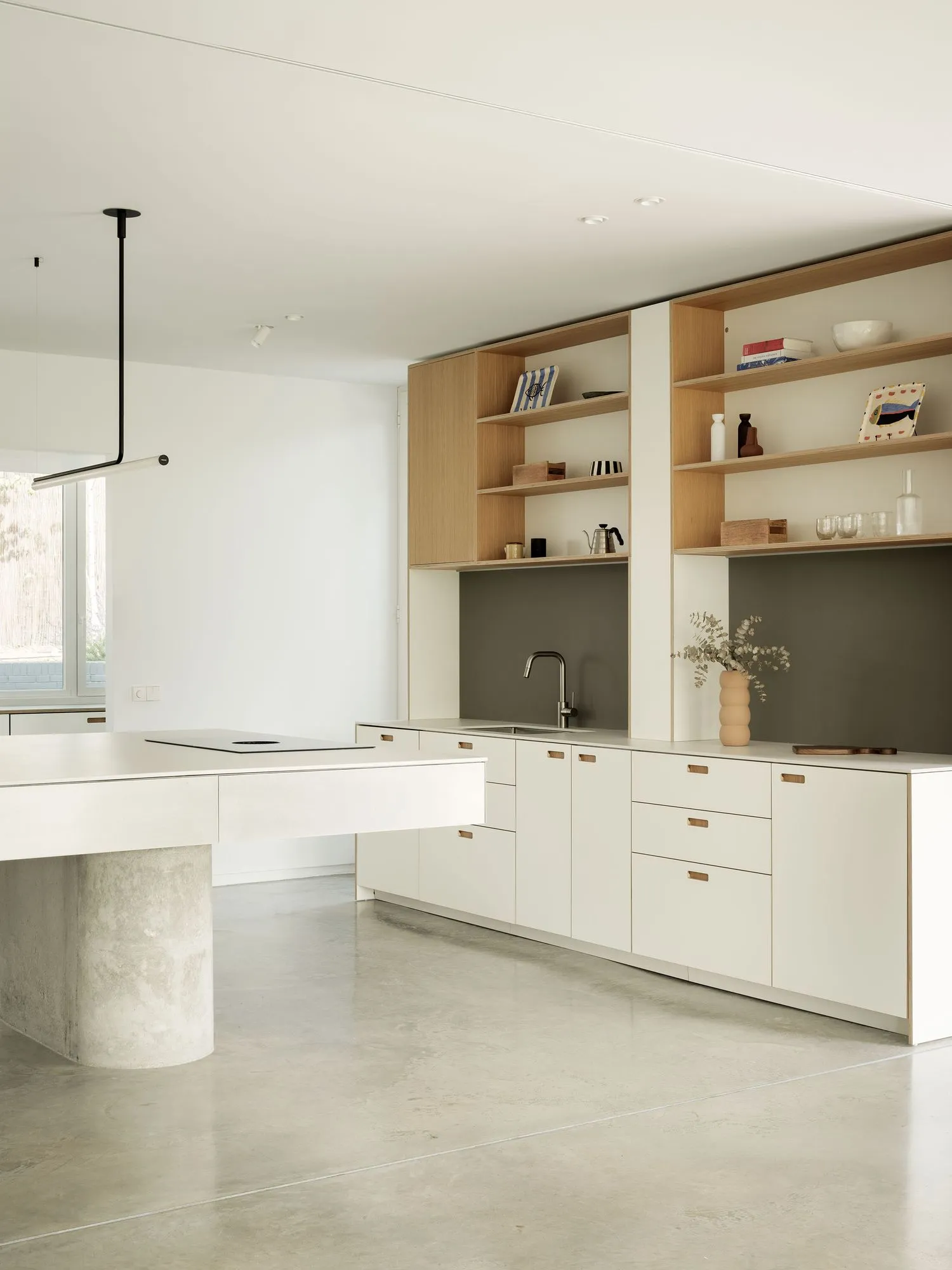 Modern minimalist kitchen featuring concrete countertops, wood cabinetry, and metal accents.
