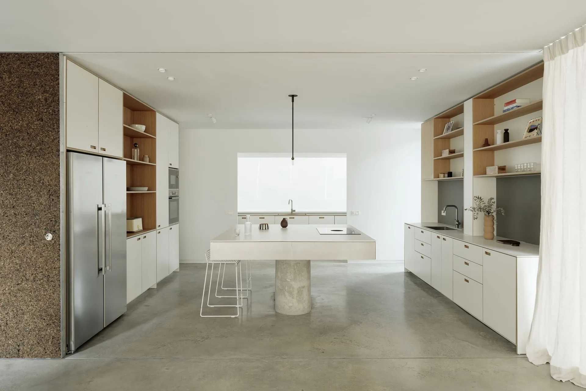 A modern minimalist kitchen with a concrete countertop, stainless steel appliances, and white cabinetry.