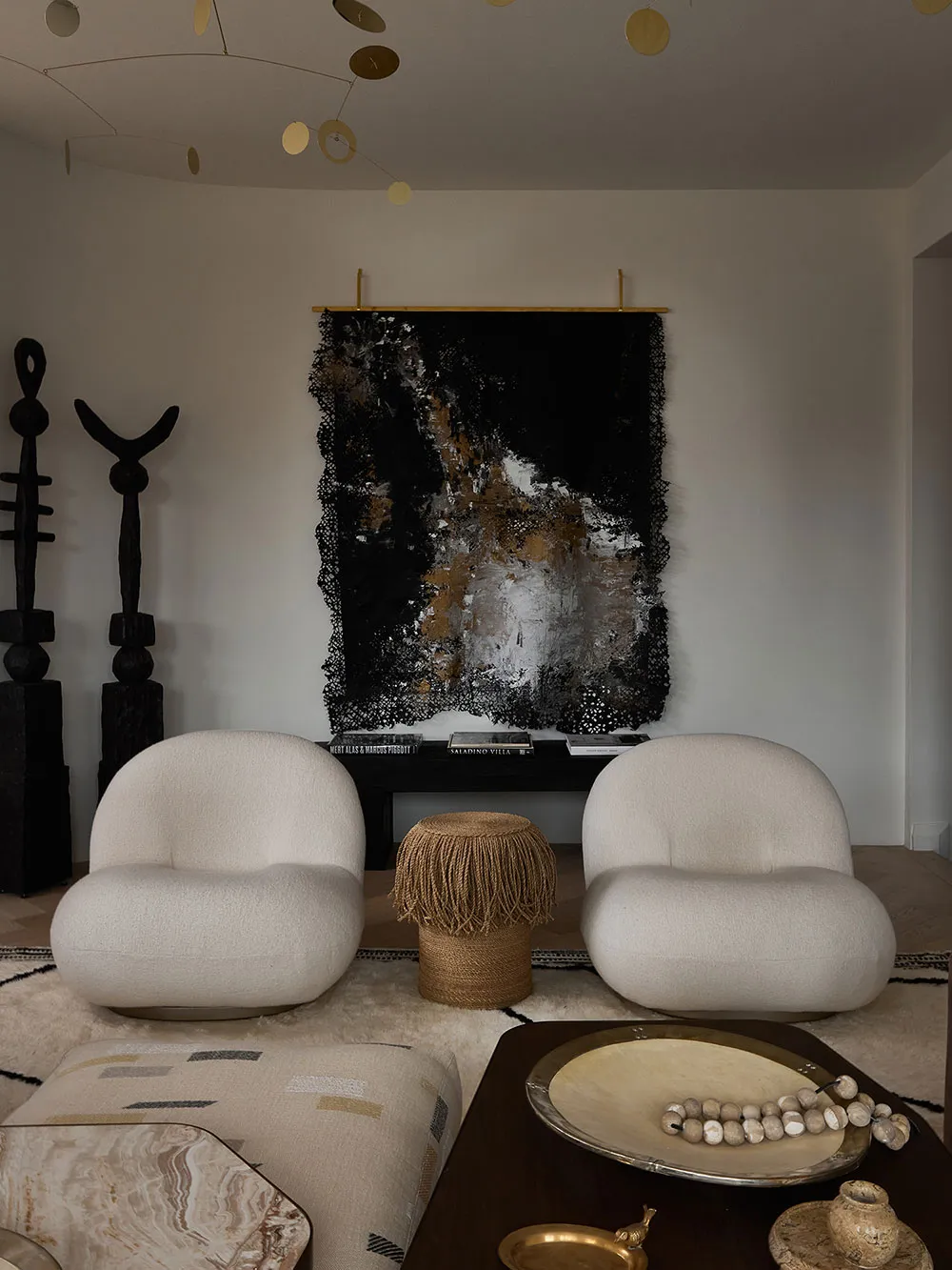 Interior design featuring white upholstered chairs, abstract art, and mixed-media decor.