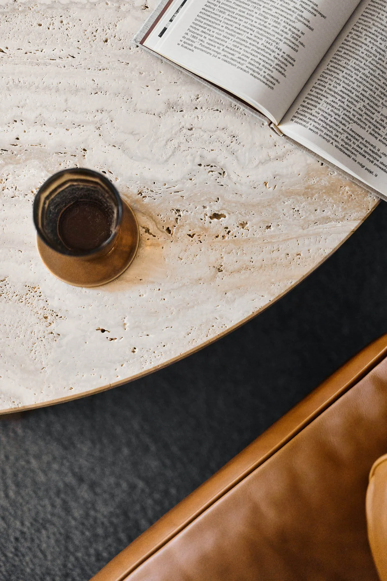 A minimalist interior design featuring a marble table with a book and a drink.