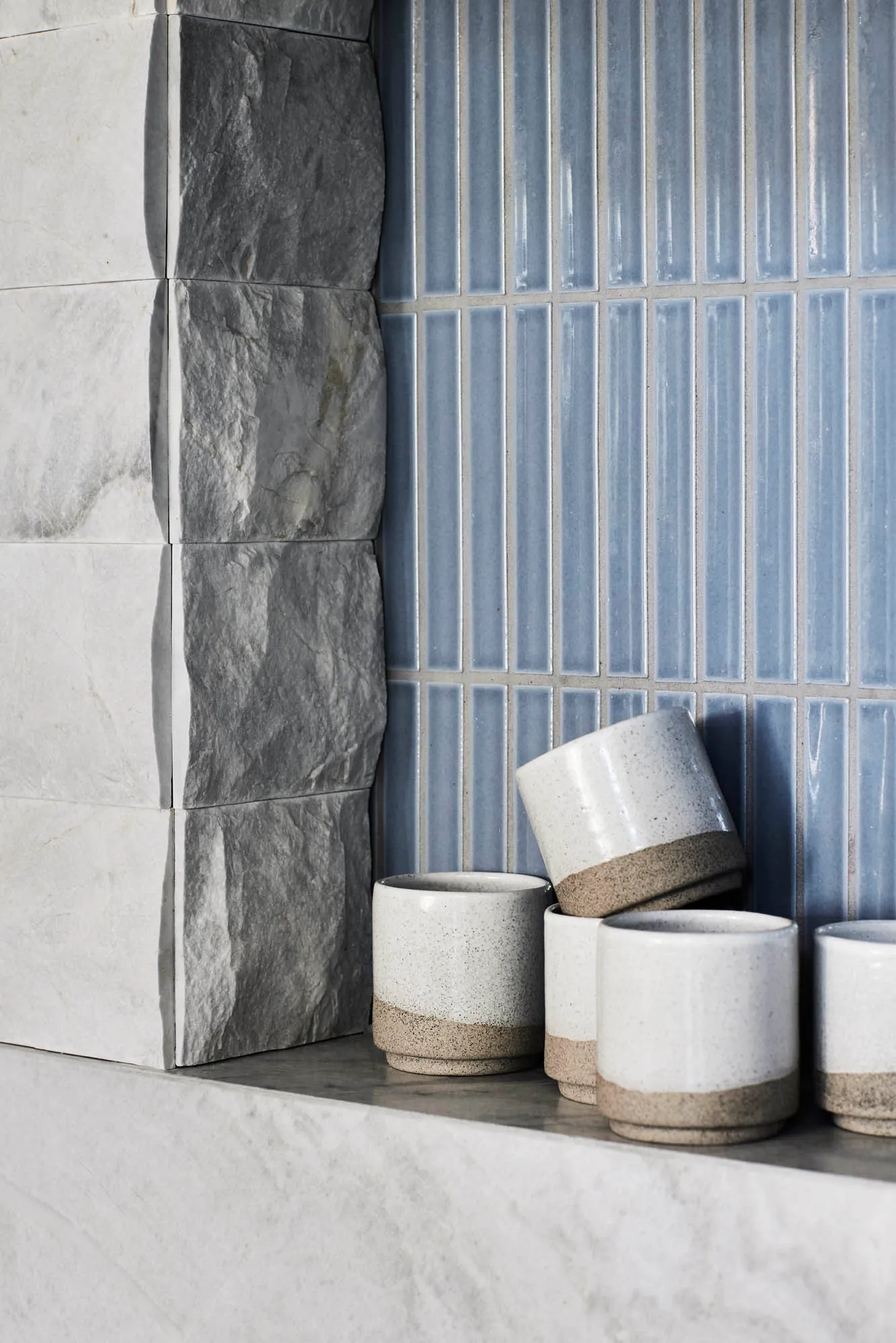 White ceramic cups with a brown base and blue ceramic tiles on a wall