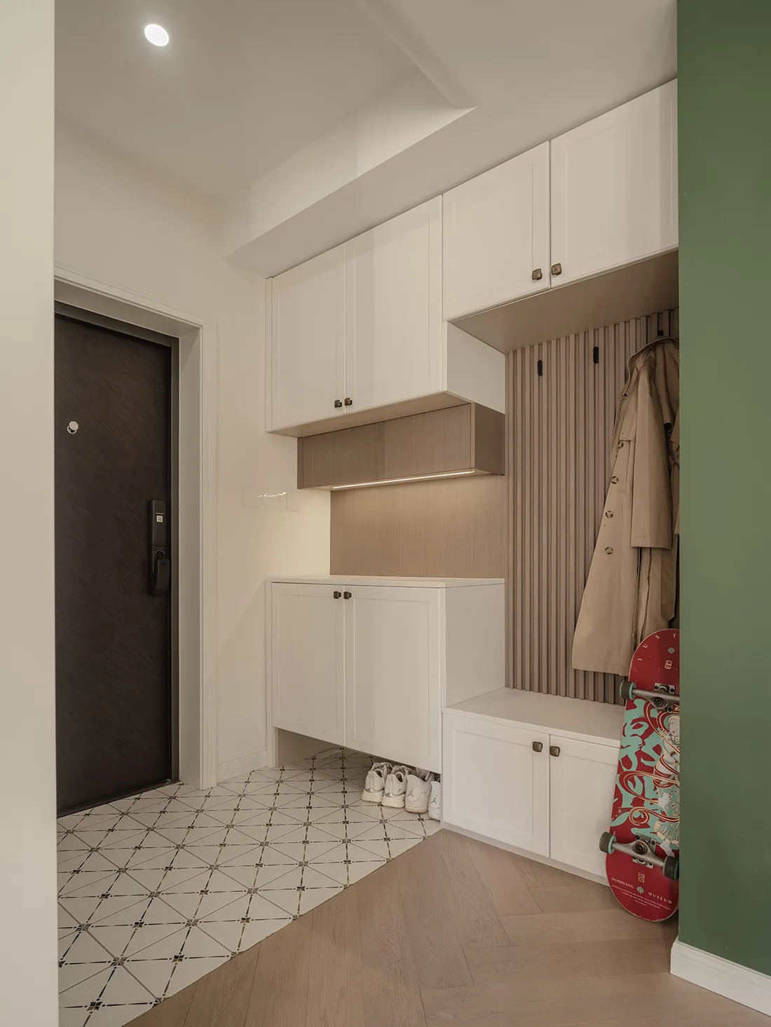 A modern entryway featuring white cabinets with wooden accents and built-in shoe storage beneath