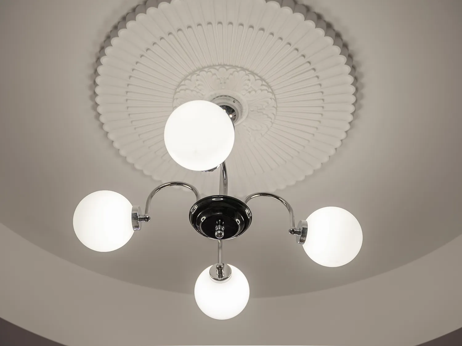 A minimalist ceiling light fixture with metal elements against a plain background.