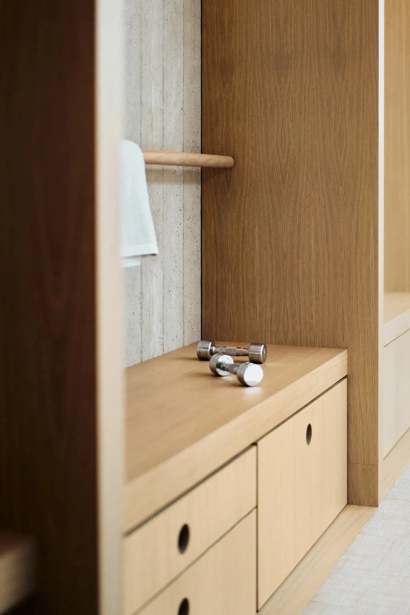Closeup of a minimalist closet with wooden cabinets and a towel hanging on the rack.