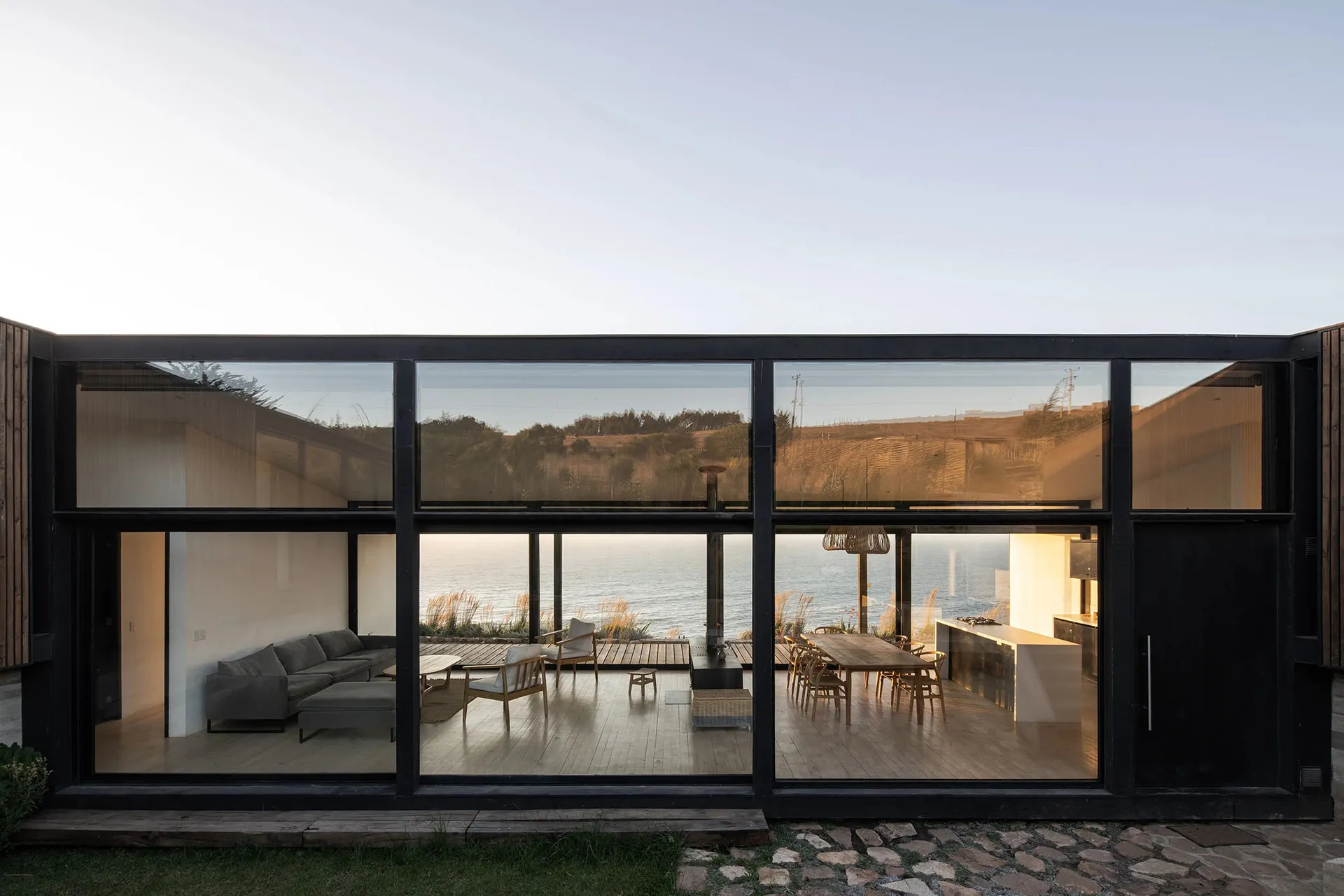 Modern minimalist residential patio enclosed with glass walls overlooking the ocean.