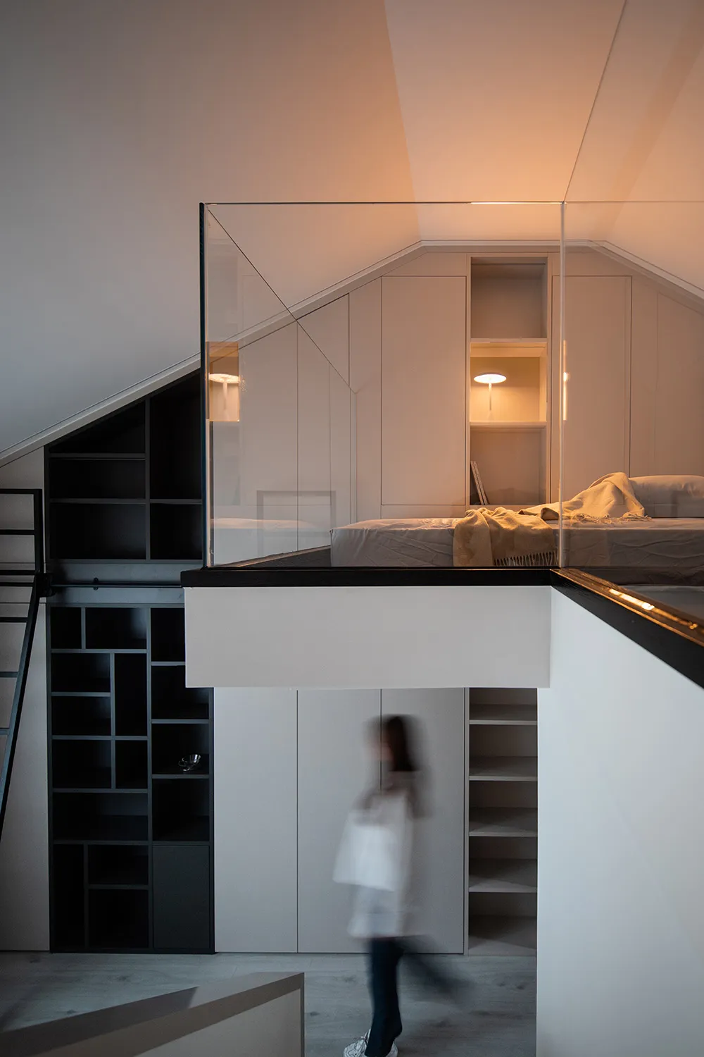 A modern minimalist bedroom featuring white walls, a black loft bed, and glass partitions.