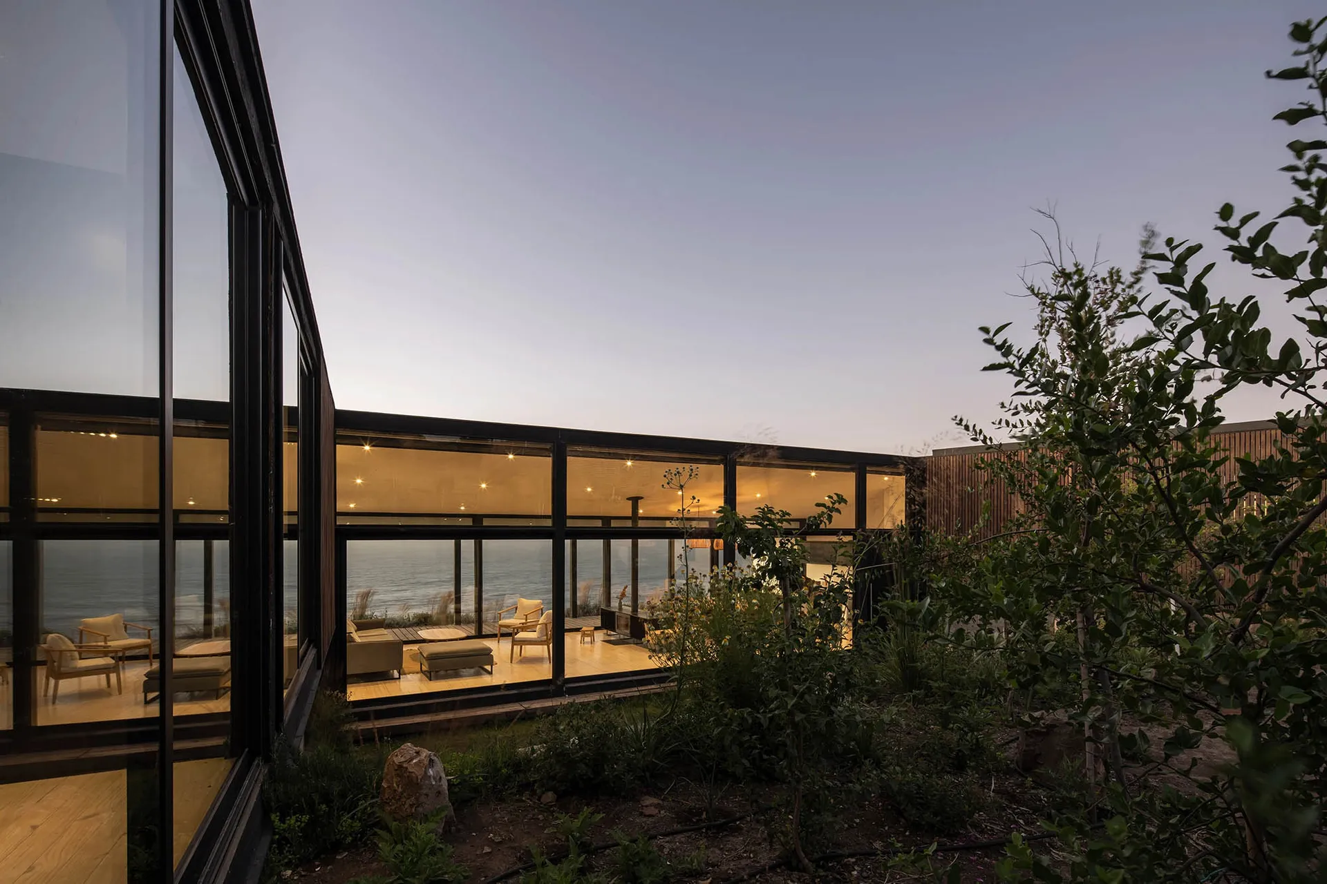 A modern residential interior featuring glass walls and wooden flooring.