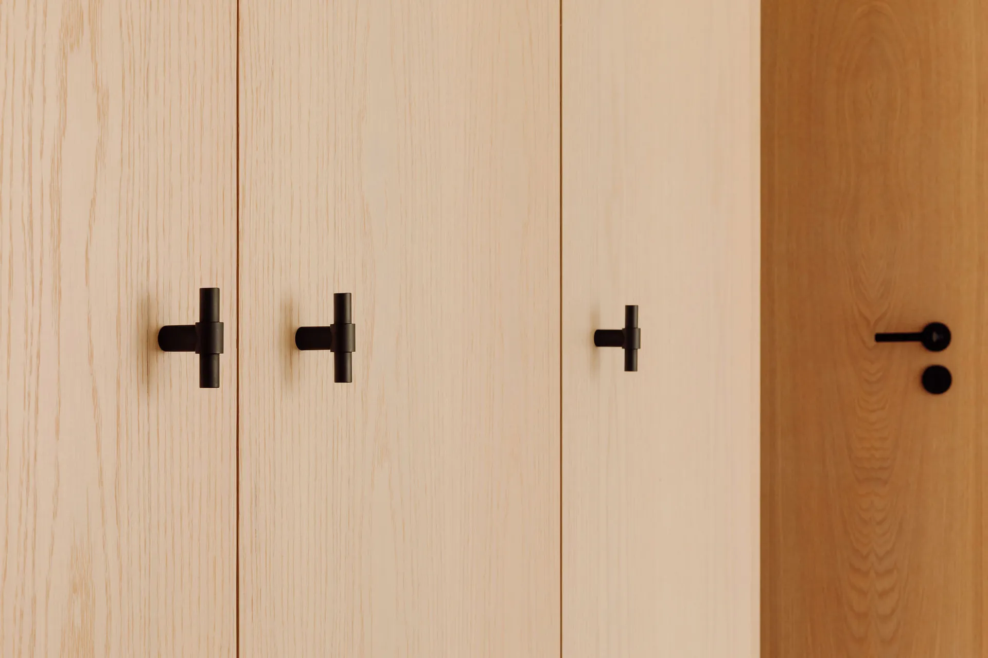 Black minimalist drawer knobs on light-colored wooden doors