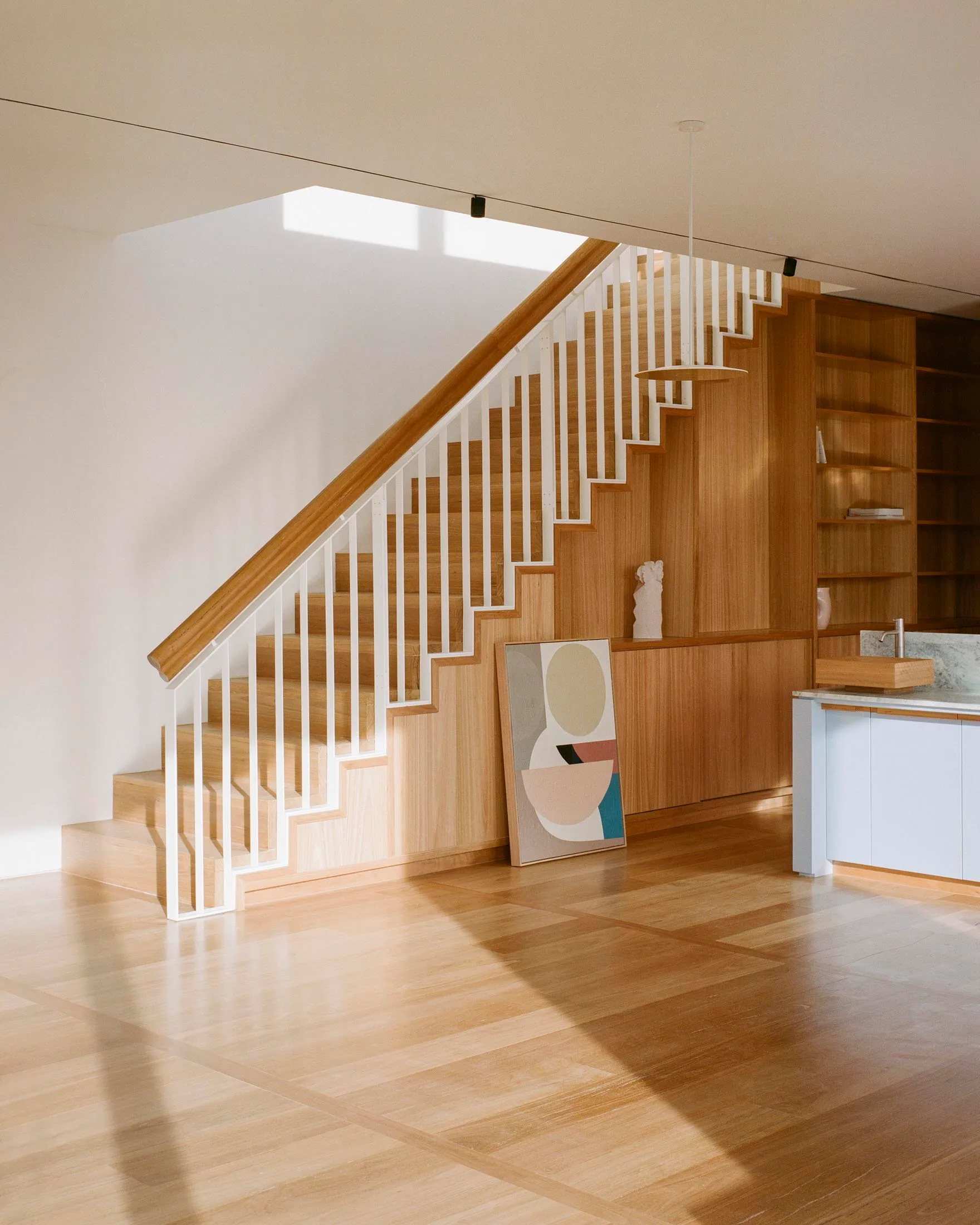 Modern interior design featuring wooden flooring and stairs with white railings.