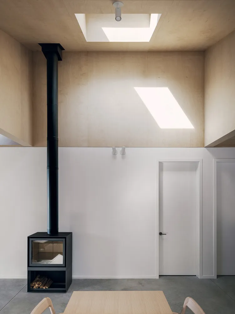 A modern living room featuring wooden paneling, a skylight, and a fireplace.