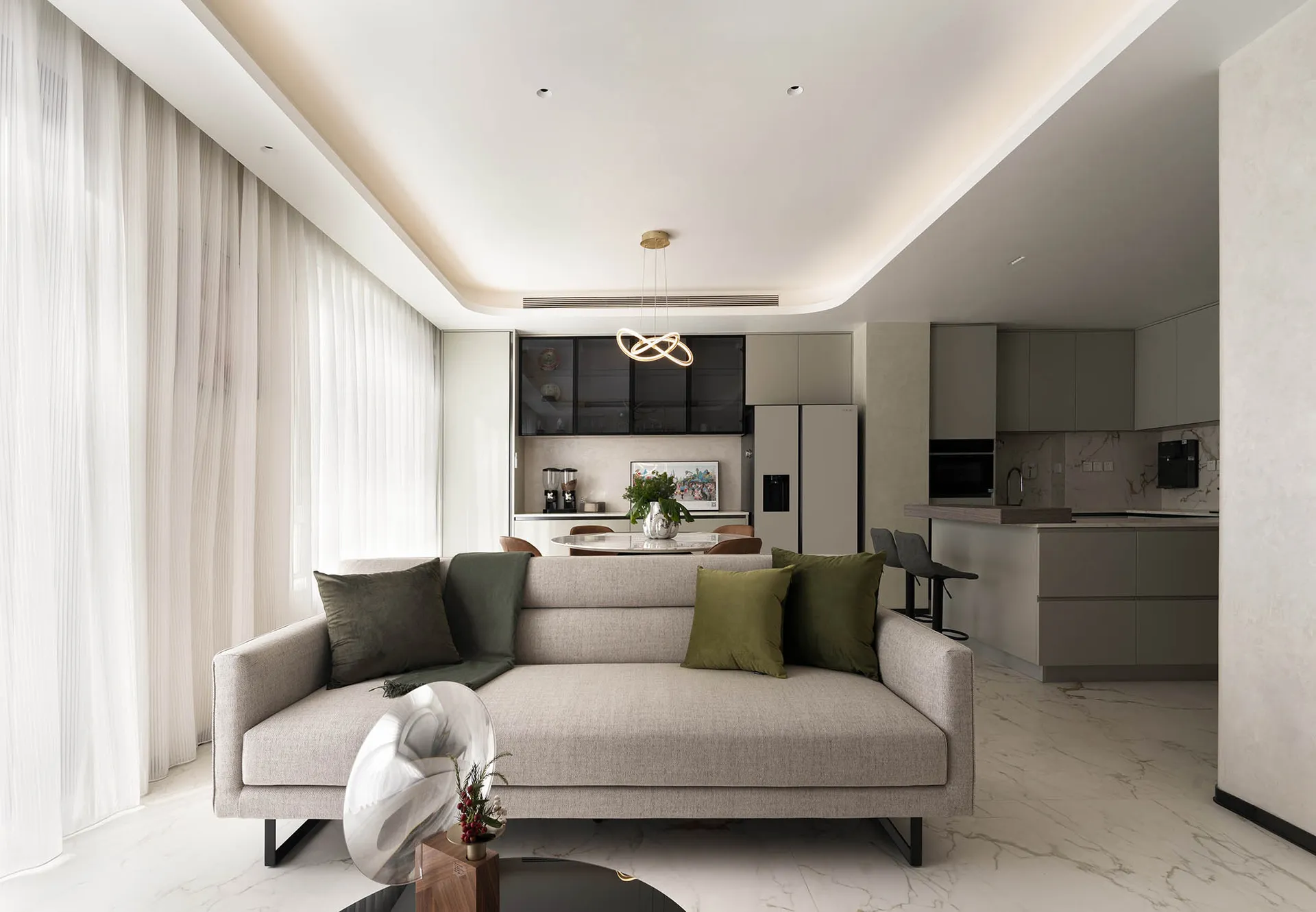 Modern minimalist living room with gray couch, green pillows, and a contemporary chandelier.