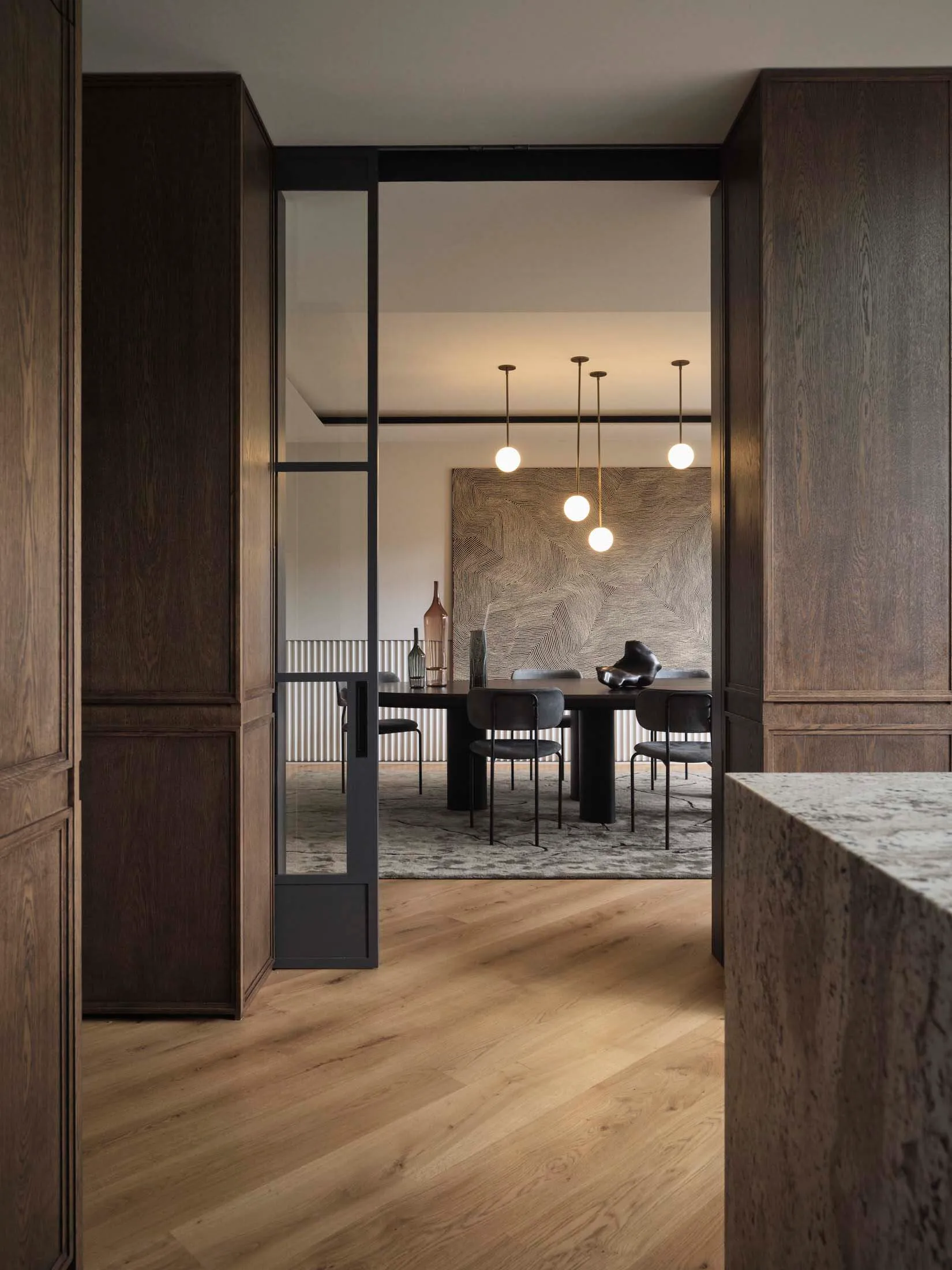 Dining room with minimalist decor, featuring a black dining table with black chairs and pendant lights above.