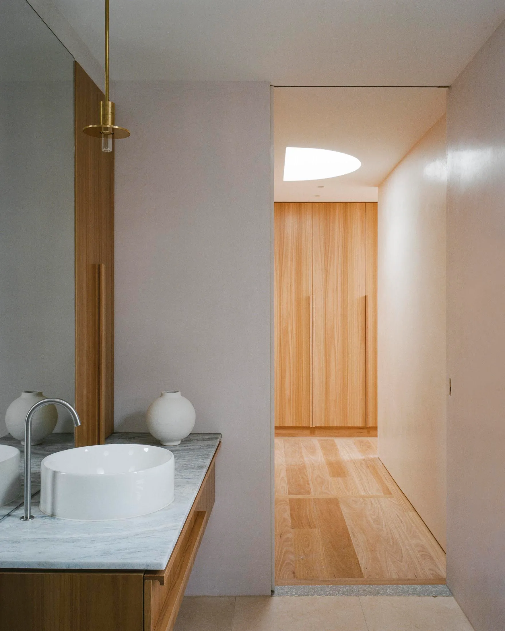 A minimalist bathroom with white porcelain sinks and natural wood elements.