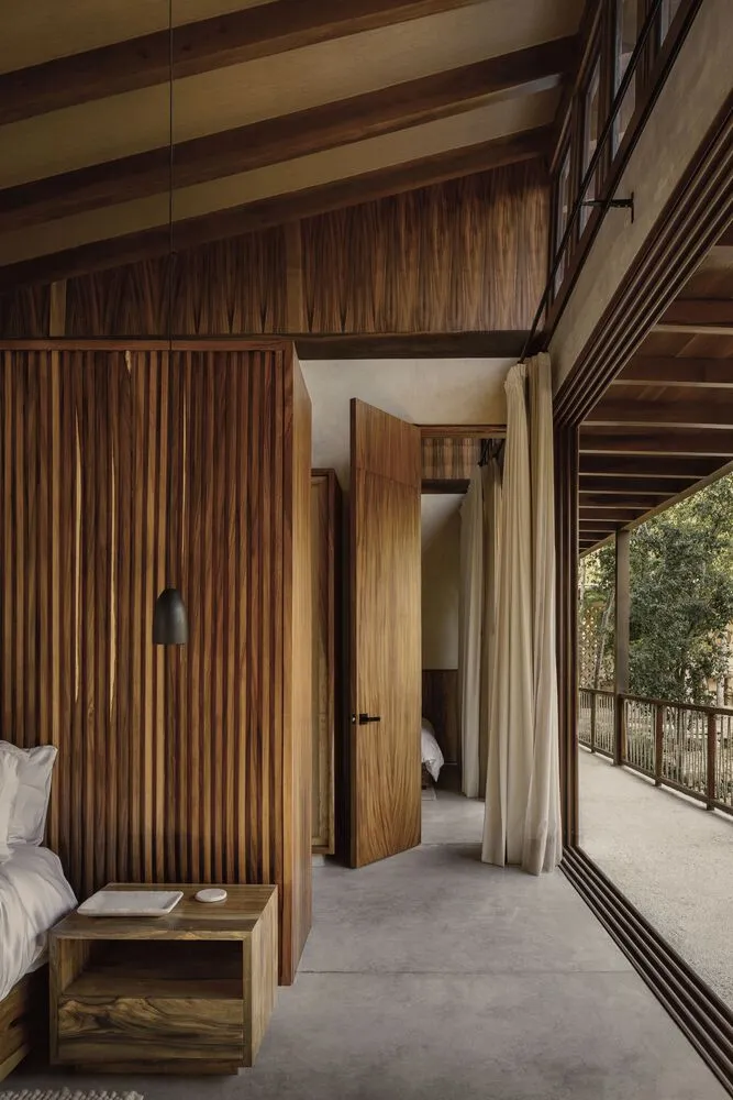 A minimalist bedroom with wooden walls and floors, featuring an open-plan design and natural light.