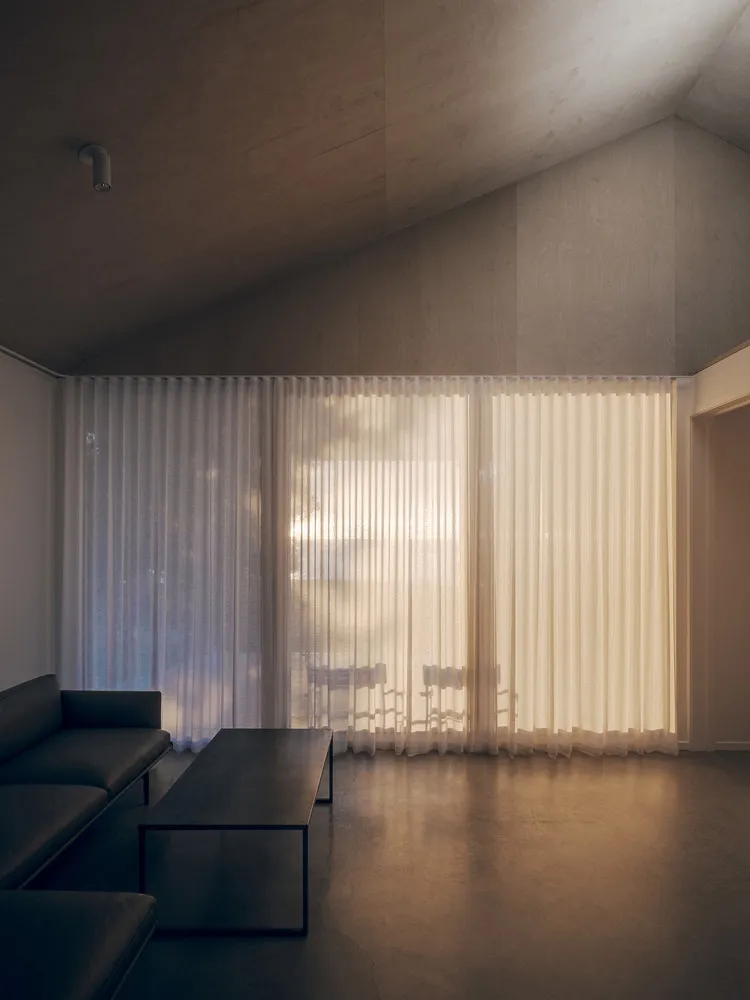 A minimalist living room featuring fabric curtains on the window.