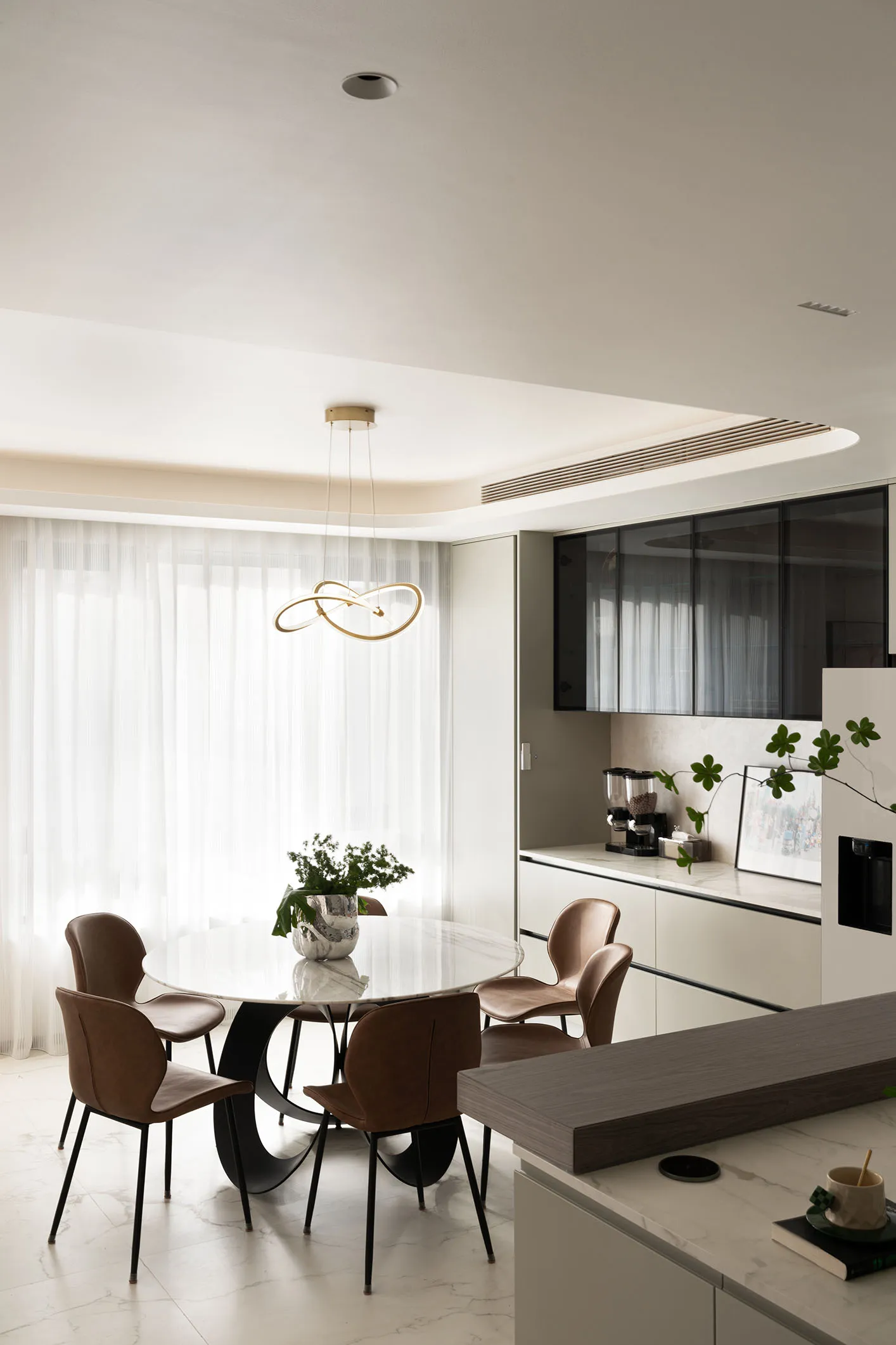Modern kitchen with marble table, leather chairs, and floating glass cabinets.