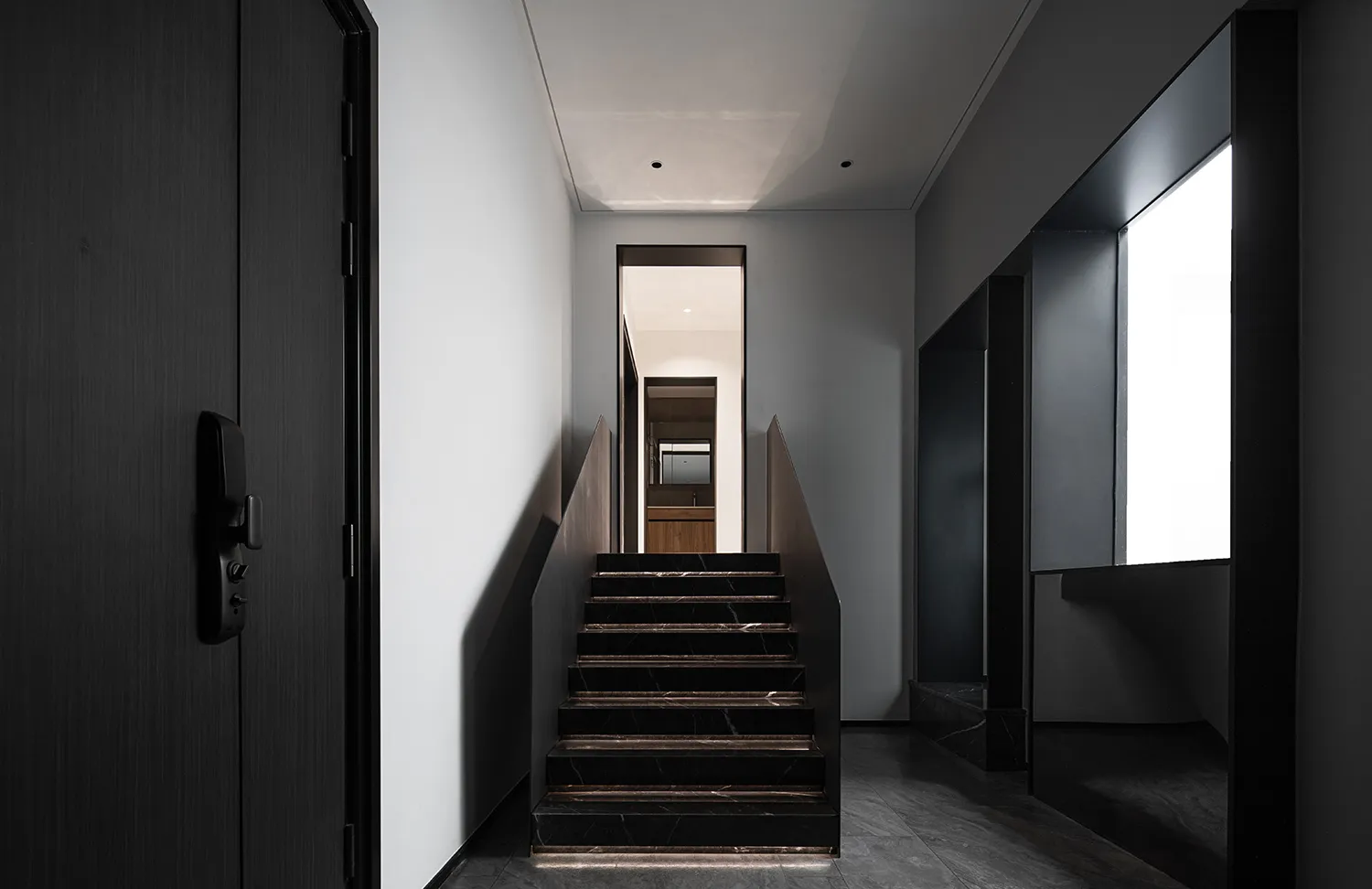 Modern minimalist staircase with black marble steps and black walls.