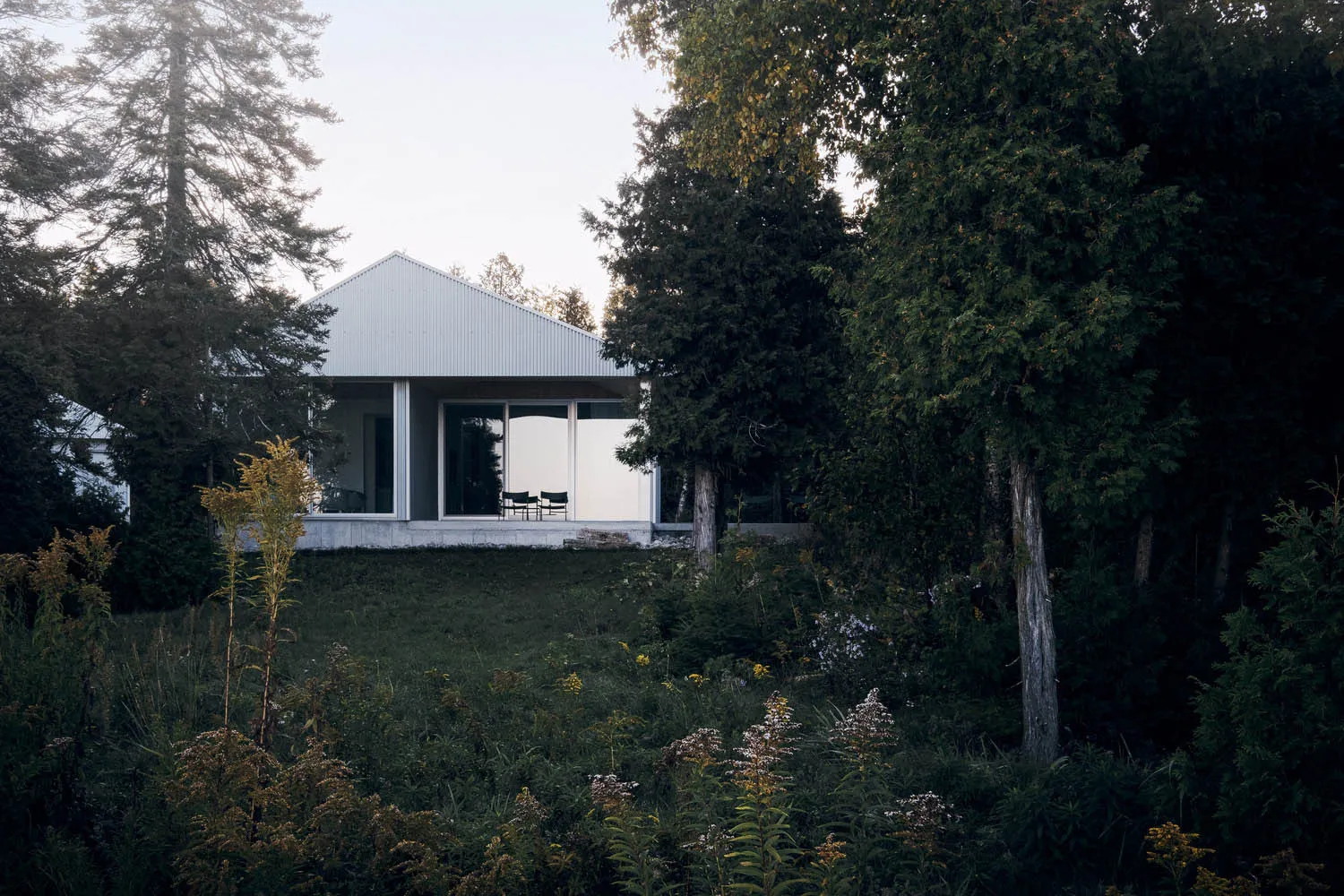 A modern house with a metal-clad exterior, featuring large windows and a minimalist design.