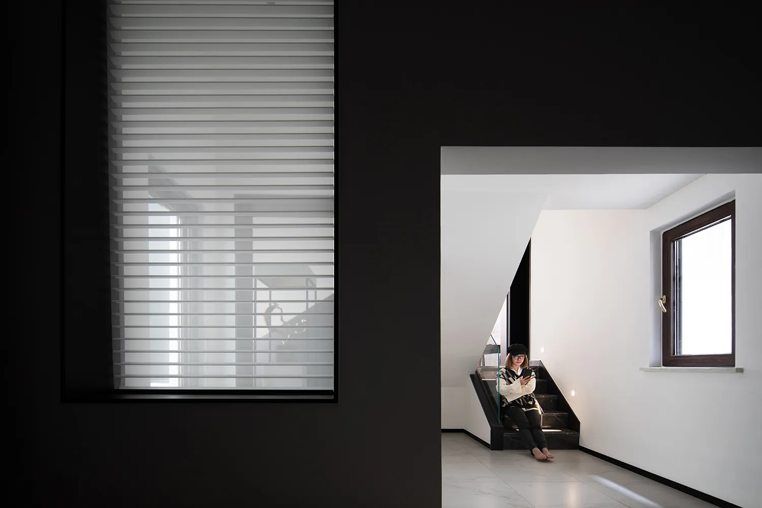 A minimalist modern residential interior with white concrete flooring, white walls, and large glass windows.