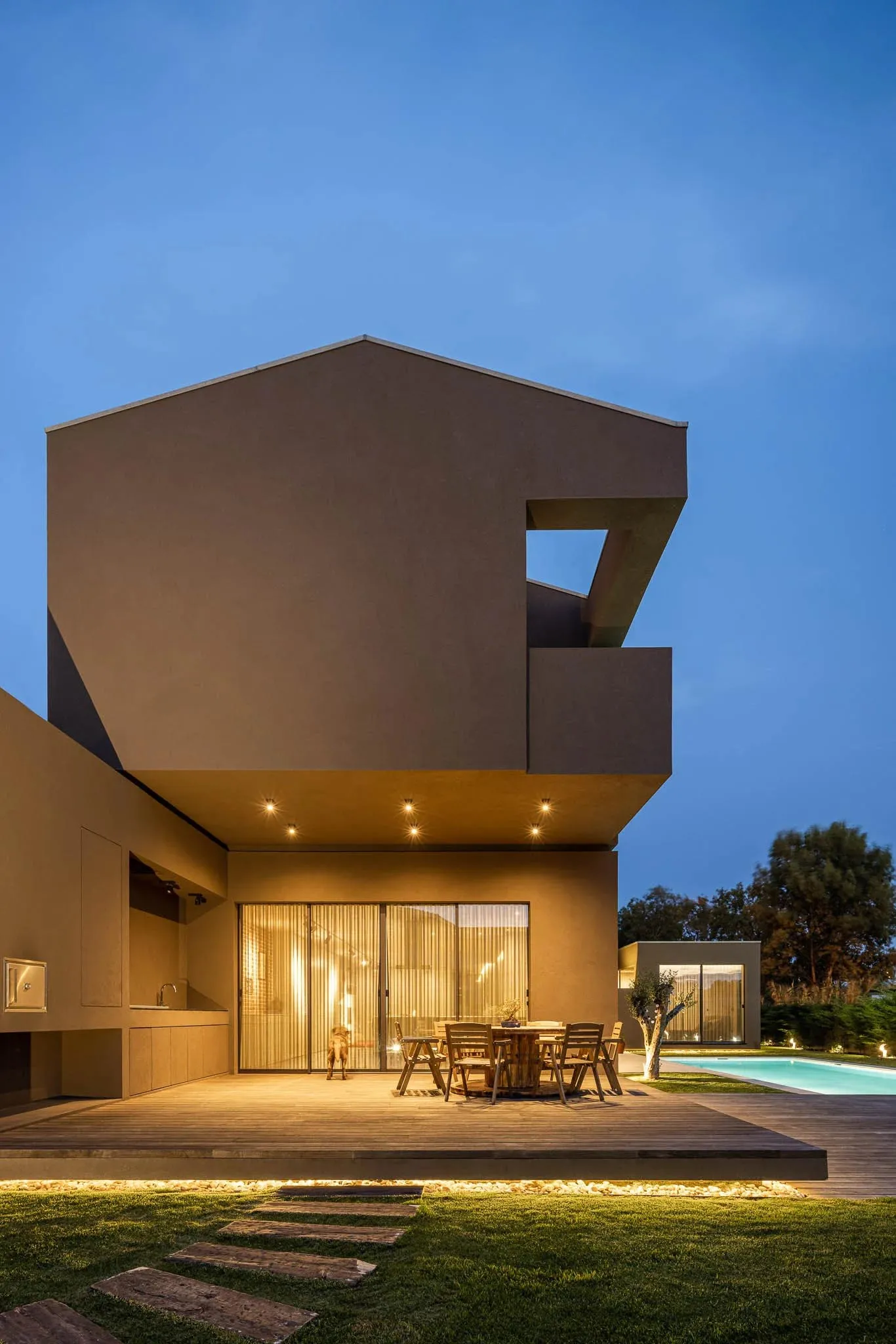 Modern house exterior with wood, concrete, and glass materials at dusk.