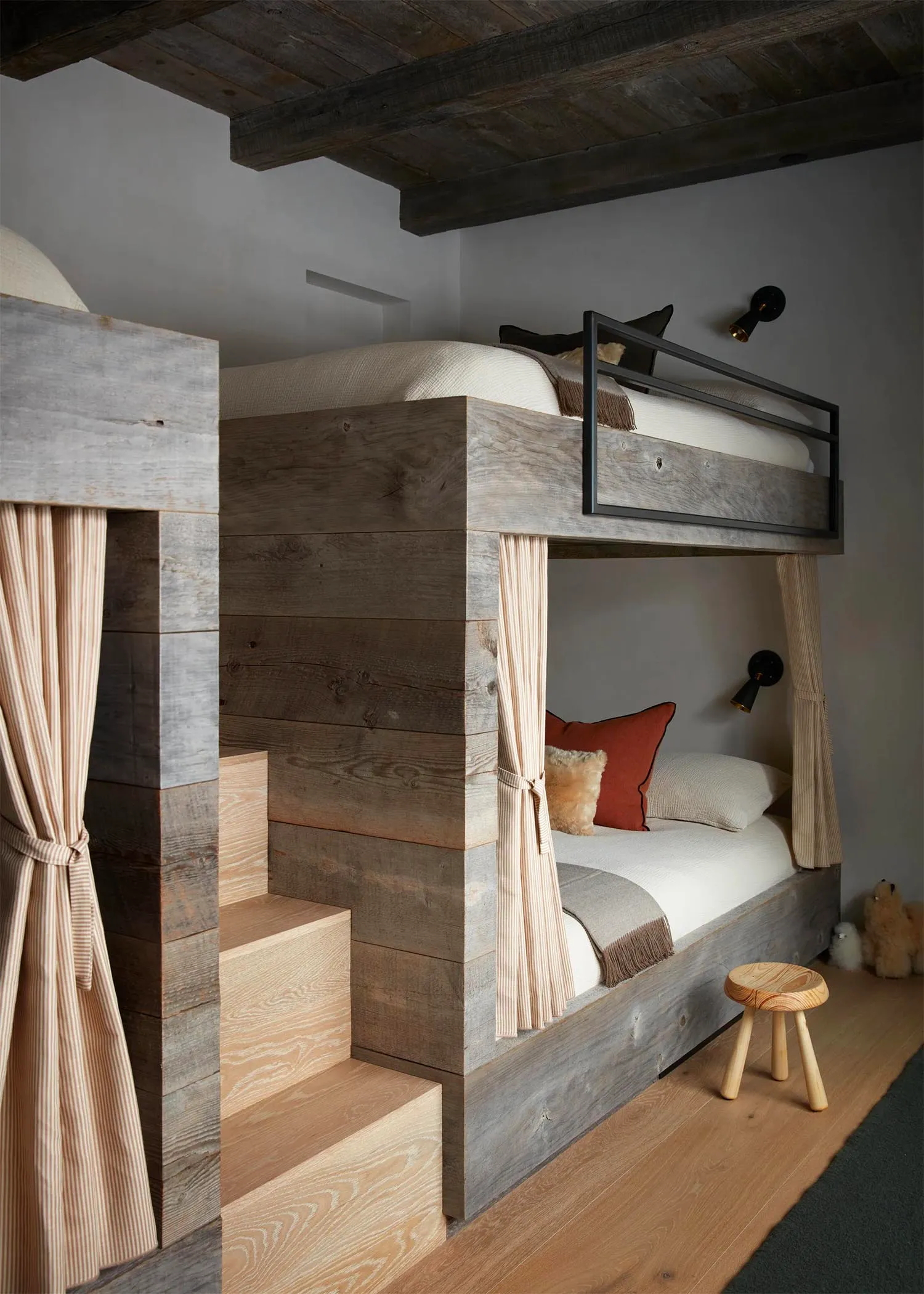 Modern bedroom featuring a wooden bunk bed with stairs leading to the top bunk and a cozy sleeping area with pillows and blan