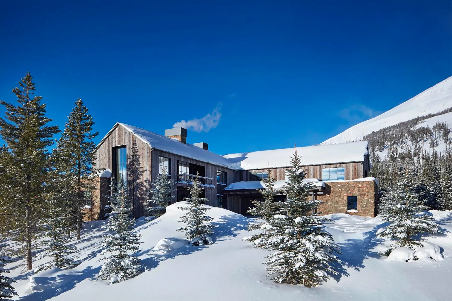 Modern residential architecture featuring wood exterior and covered in snow.