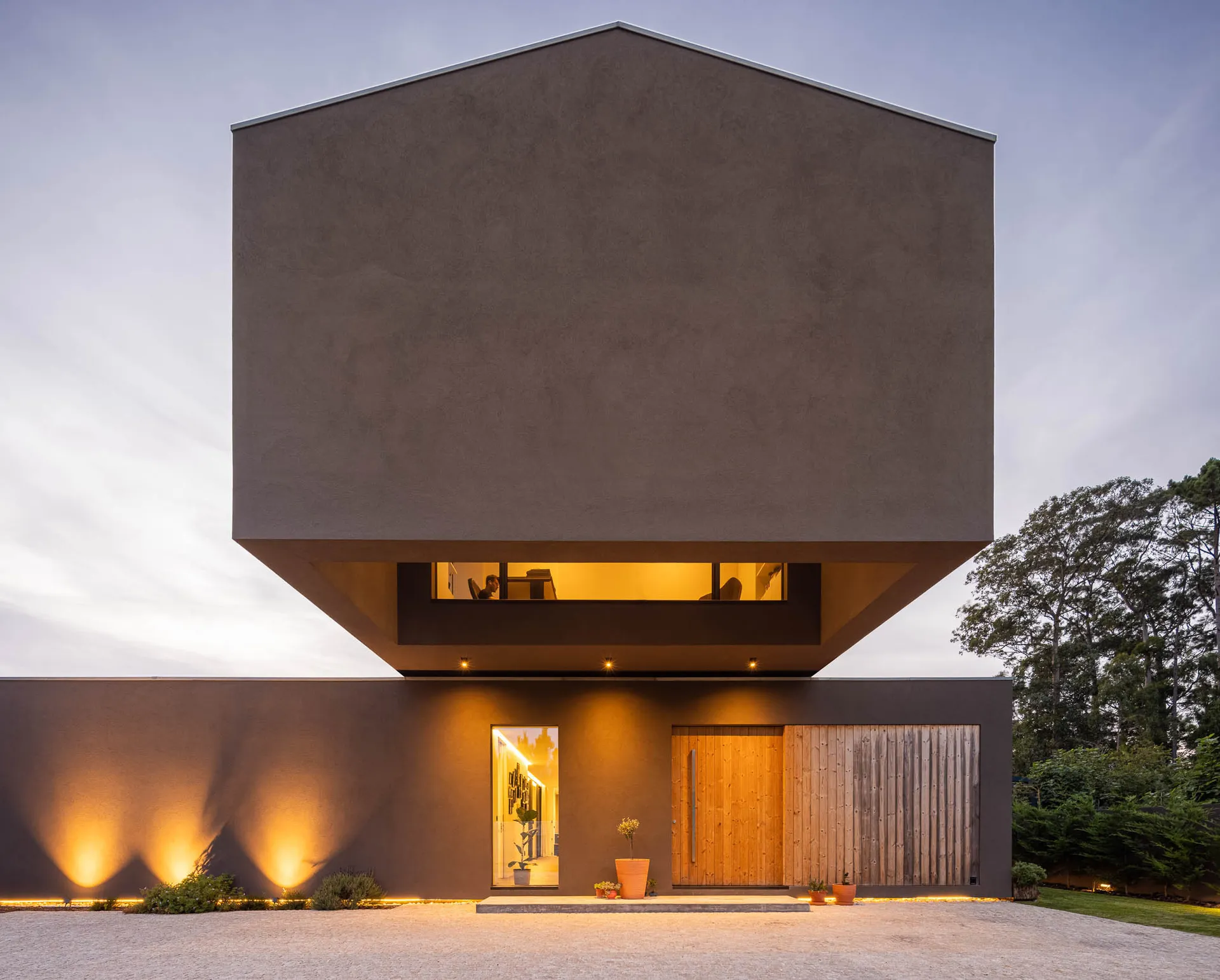 A modern residential building with a concrete exterior and warm indoor lighting.