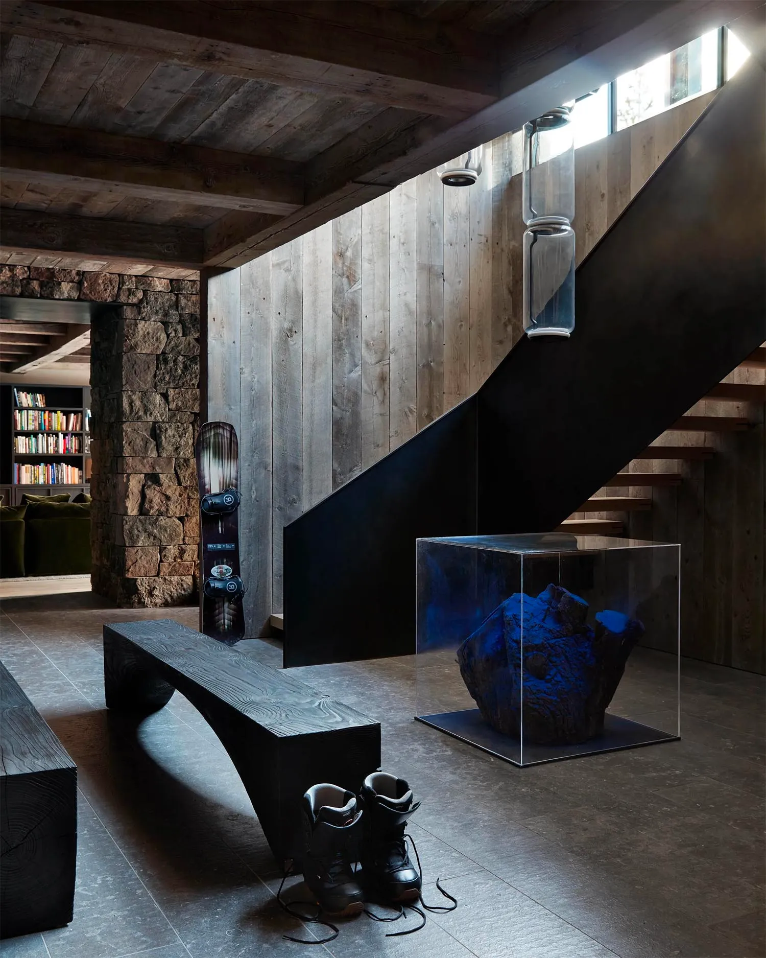 Modern industrial interior featuring wooden bench, concrete floor, stone accent wall, metal railings, and concrete steps. Inc