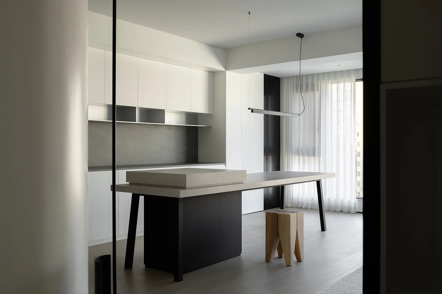 A minimalist modern kitchen with a concrete island and white cabinets.