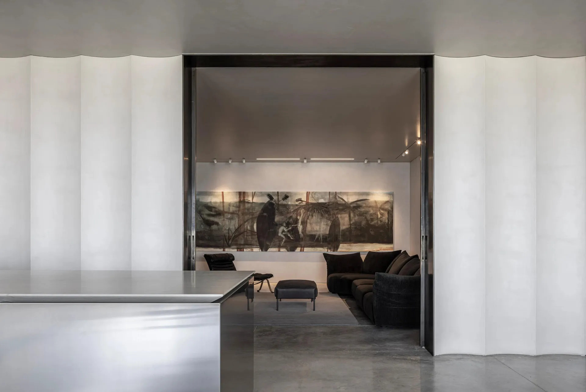 Modern minimalist interior featuring a concrete wall, a large abstract painting, and black furniture.