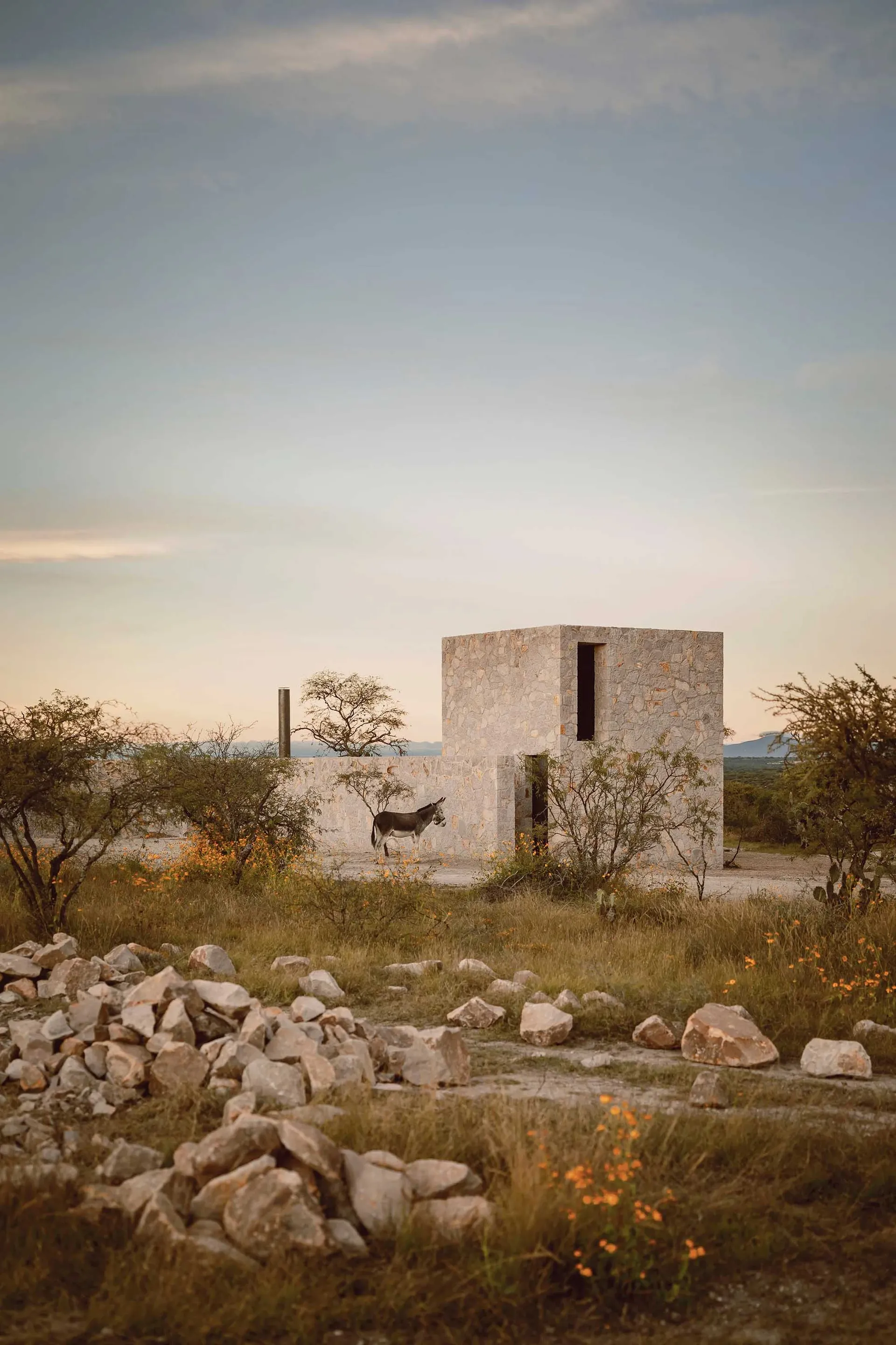 A minimalist building constructed of stone materials with a simple, open design.
