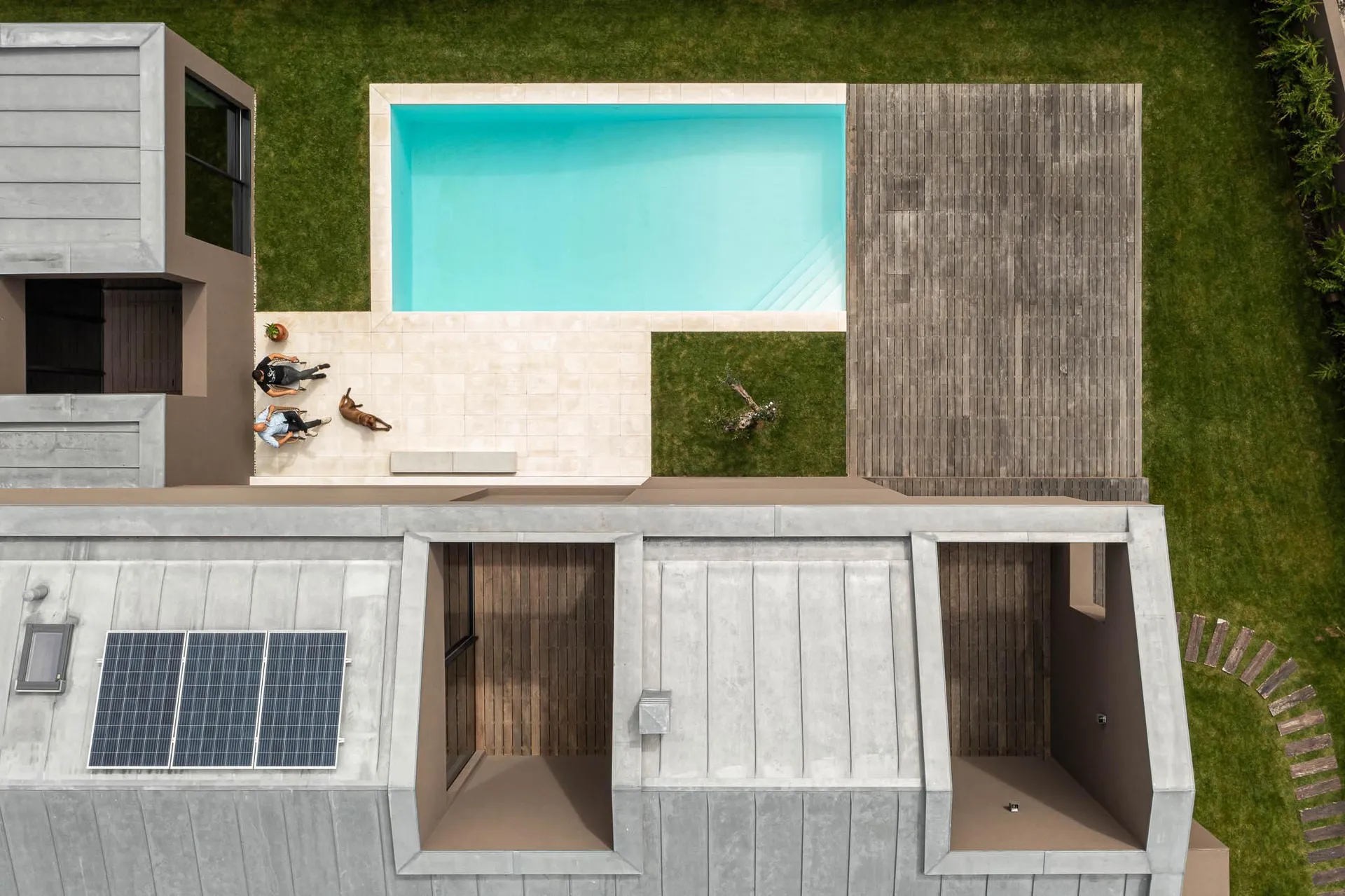 A modern house with a concrete exterior features a swimming pool and deck area.