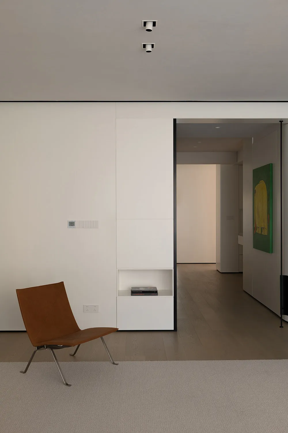 Modern minimalist living room with wood flooring and a brown leather chair.