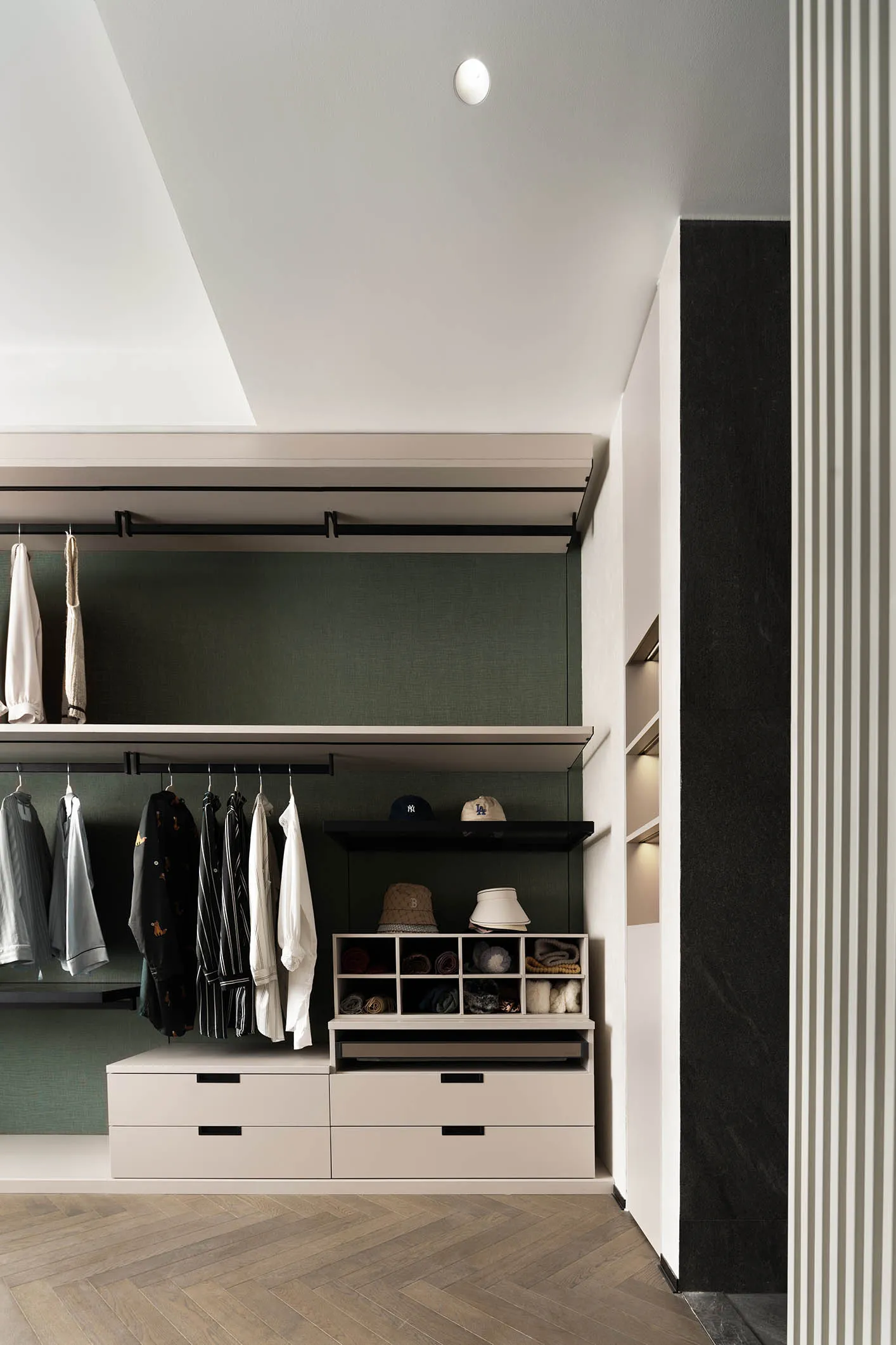 A modern closet with white, black, and green color scheme, featuring metal rods, wooden drawers, and shelves.