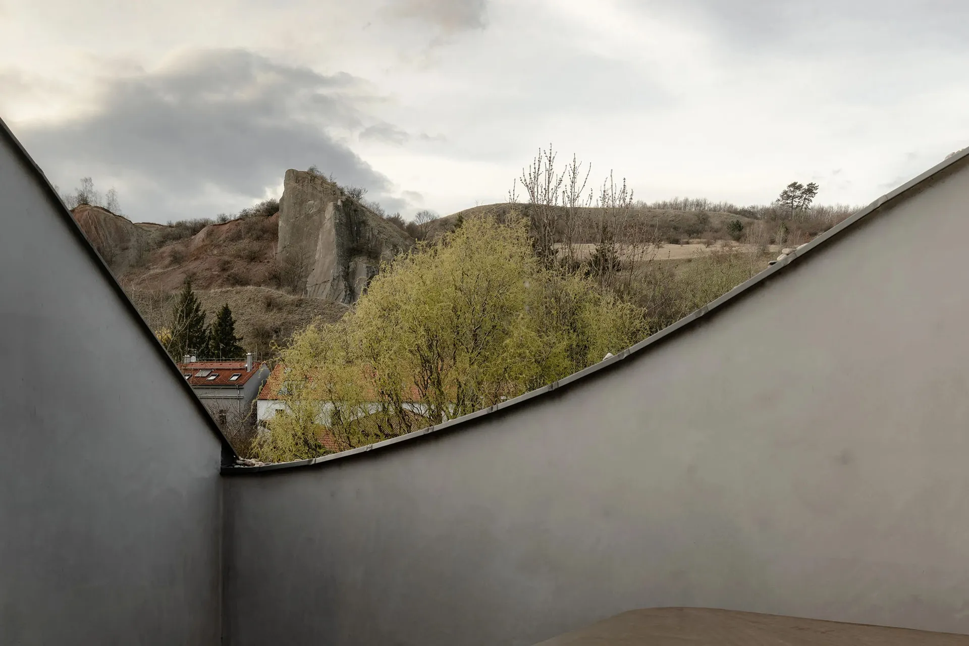 Minimalist interior with concrete walls and a view of a rocky hillside.