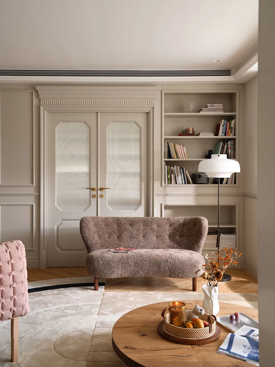 Circular rug with a modern minimalist living room setup, featuring a plush sofa, bookshelves, and a round wooden coffee table